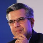 Portrait of a thoughtful businessman in a suit, wearing eyeglasses, captured in an indoor corporate setting.