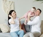 Loving parents playing with their baby daughter at home, capturing moments of joy and togetherness indoors.