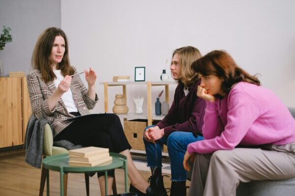 A counselor having a discussion with two students in an inviting, modern interior space.